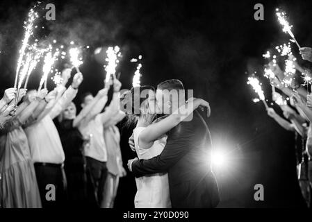 feu froid des bougies de gâteau et des feux d'artifice dans les mains des gens autour des jeunes mariés Banque D'Images