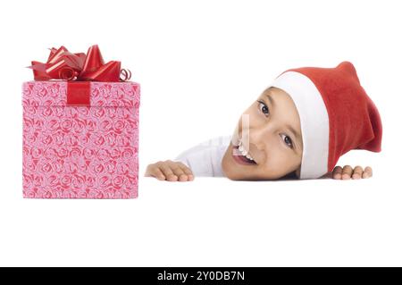 Garçon dans le chapeau rouge de noël tenant une boîte cadeau avec expression heureuse sur son visage avec copyspace blanc pour coller votre annonce ou bannière isolé sur BA blanc Banque D'Images