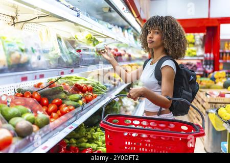 Femme de beauté curieuse latine magasinant des aliments frais dans le supermarché dans la section légumes Banque D'Images