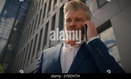 Sérieux irrité confiant entrepreneur émotionnel parler conflit smartphone expliquer discuter de problème de travail parler homme d'affaires senior d'âge moyen Banque D'Images