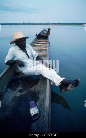 Les hommes sont assis dans leur énorme pirogue sur le fleuve Congo. Banque D'Images