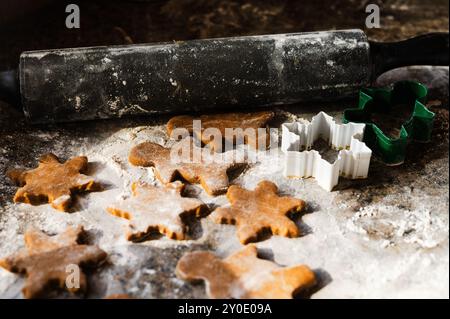 Rouleau à pâtisserie à côté des biscuits de pain d'épices fraîchement coupés, prêts pour le four Banque D'Images