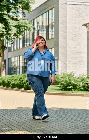 Une femme de grande taille avec les cheveux roses marche dans une rue de la ville, parlant au téléphone avec un grand sourire. Banque D'Images