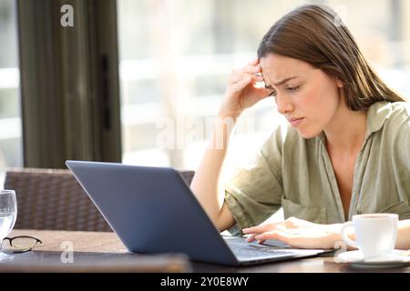 Femme inquiète se plaignant dans un bar vérifiant les mauvaises nouvelles sur ordinateur portable Banque D'Images