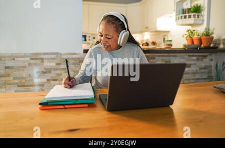 Femme africaine senior faisant webinaire numérique à la maison - Joyful vieillesse style de vie et concept de technologie - Focus sur le visage Banque D'Images