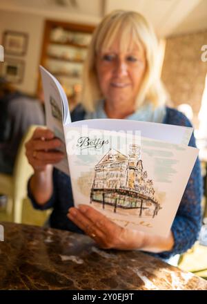 Femme regardant un menu dans Betty's Tea Rooms, Harrogate, North Yorkshire, Angleterre, Royaume-Uni Banque D'Images