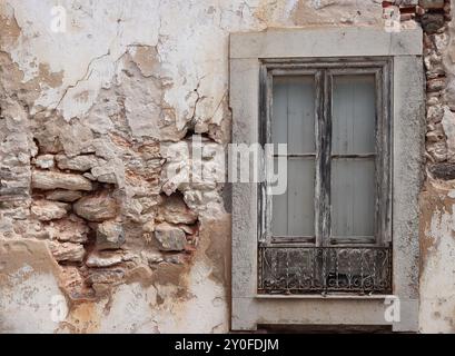 Vieux mur en pierre blanche endommagée avec plâtre ruiné et fenêtre vintage Banque D'Images