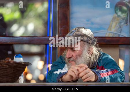 Tbilissi, Géorgie - 8 octobre 2023 : un homme plus âgé est assis confortablement dans un café, regardant attentivement tout en dégustant son café. Banque D'Images