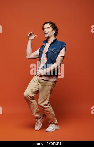 Un homme émotionnel danse joyeusement avec énergie sur un fond audacieux. Banque D'Images