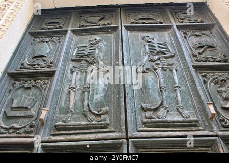 Portes en bois sculptées ornées avec des squelettes et des motifs religieux ; Cathédrale baroque Monopoli italie monopoli avec des squelettes de cardinaux, la porte en bois, des crânes en pierre sculptée et l'intérieur Banque D'Images