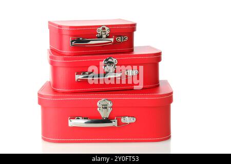 Ensemble de bagages assortis empilés les uns sur les autres. Trois tailles différentes de valise rouge isolé sur blanc avec un léger reflet. Banque D'Images