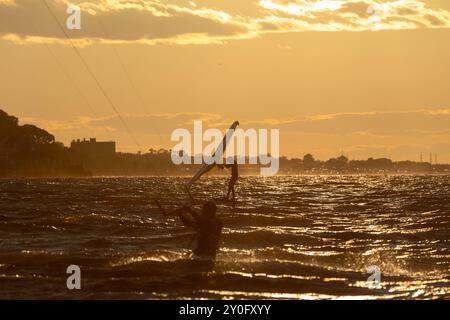 Sandy Hook, New Jersey - 21 août 2024 : les kitesboarders prennent l'eau alors que le soleil se couche sur Sandy Hook par une magnifique nuit d'été Banque D'Images