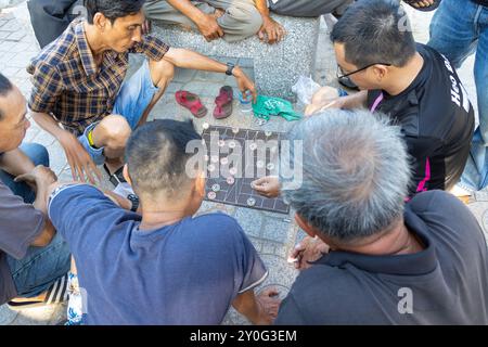 Nha Trang, Vietnam - 22 avril 2024 : des vietnamiens âgés et d'âge moyen jouent au xiangqi (jeu de société chinois) dans la rue en squattant. Deux hommes p Banque D'Images