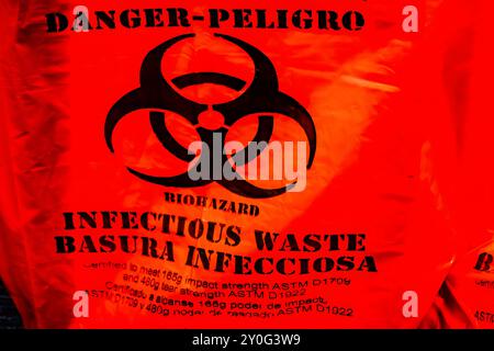 Gros plan d'un sac orange avec symbole de risque biologique et étiquette « danger, déchets infectieux » Banque D'Images