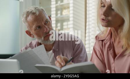 Fatigué pensif couple caucasien famille grands-parents femme mature femme âgée homme âgé retraité masculin parle d'affaires travaillant avec des documents Banque D'Images