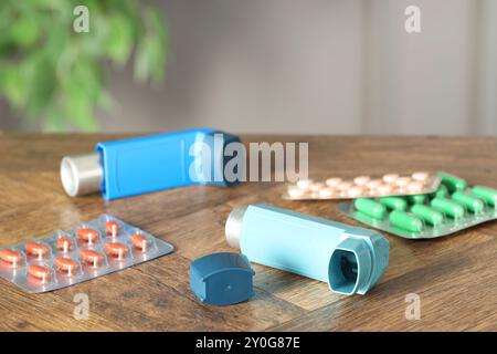 Inhalateurs et pilules sur la table en bois à l'intérieur, gros plan. Traitement de l'asthme Banque D'Images