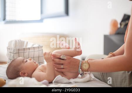 Les mains d'une femme changeant la couche d'un bébé sur un lit. Maternité et famille. Banque D'Images