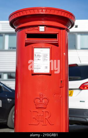 Vue de face rapprochée d'une boîte aux lettres Royal mail extérieure devant des voitures stationnées et un immeuble de bureaux. Banque D'Images