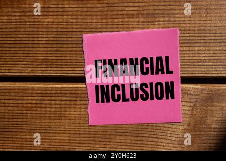 Message d'inclusion financière écrit sur un morceau de papier rose déchiré déchiré avec fond en bois. Symbole conceptuel d'inclusion financière. Copier l'espace. Banque D'Images