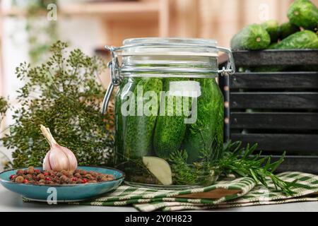 Concombres marinés en pot, herbes et épices sur la table, gros plan Banque D'Images