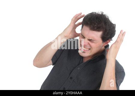 Jeune homme frustré et stressé tenant la tête dans les mains tout en se tenant debout sur fond blanc Banque D'Images