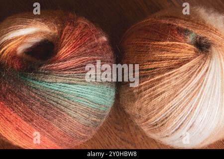 Deux boules de fil multicolores sur la table. Fil à tricoter brillant. Passe-temps de tricot. Concept artisanal. Fils de laine et de laine d'alpaga. Mode automne Banque D'Images