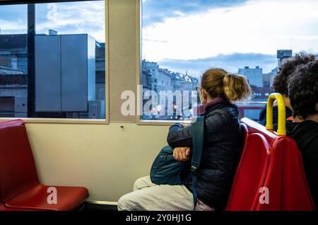 Vienne, Autriche, 23 août 2022. Vue de la ville depuis l'intérieur du métro : une femme d'âge moyen regarde par la fenêtre. Deux passagers sont derrière lui Banque D'Images