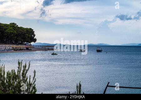 Primosten, Croatie-25 juin 2024 : plage presque vide pleine de soleil à la ville de Primosten, Croatie pendant le coucher du soleil venteux Banque D'Images