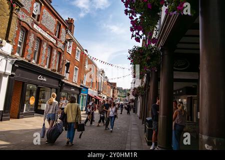 Une rue commerçante animée avec des gens marchant et transportant des sacs, entourée de bâtiments historiques en briques et de devantures de magasins à Winchester Royaume-Uni Banque D'Images