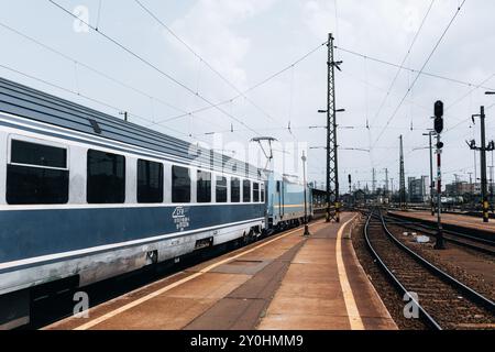 Wagons de train pour le train Budapest (Hongrie) à Timisoara (Roumanie) à la gare Keleti par une journée ensoleillée d'été avec des voies ferrées et vue sur la plate-forme. Banque D'Images