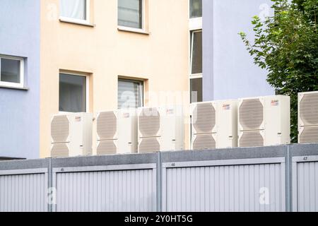 Pompes à chaleur dans une zone résidentielle, les maisons multifamiliales sont alimentées en chauffage, en refroidissement et en eau chaude sanitaire via ces appareils, montés sur le garage R. Banque D'Images