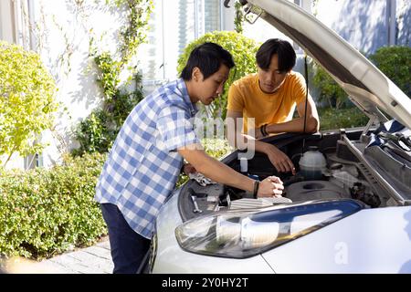 Père et fils réparant le moteur de la voiture ensemble, liant sur les travaux d'entretien Banque D'Images