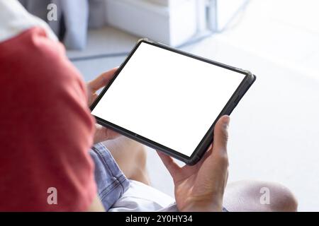 Tablette de maintien avec écran vierge, personne assise et naviguant dans le contenu, espace de copie Banque D'Images