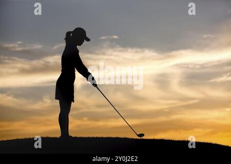 Une silhouette d'une femme golfeuse au coucher du soleil faisant un tee up sur la balle Banque D'Images