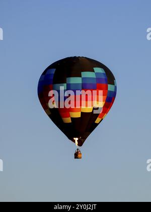 Une montgolfière colorée tirant une flamme flotte dans le ciel dans le nord de l'Idaho Banque D'Images