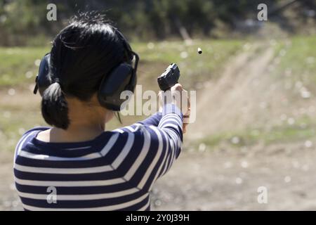 Une femme praqctices en toute sécurité tirant un pistolet sur un champ de tir dans le nord de l'Idaho Banque D'Images