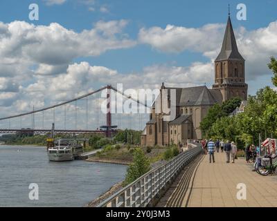 Promenade le long d'une rivière avec une église et un pont en arrière-plan, beaucoup de gens marchent ou font du vélo, emmerich, Bas-rhin, allemagne Banque D'Images