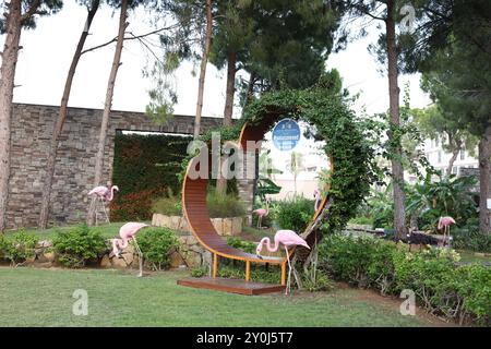 Belek, Turquie - 25 juillet 2024 : banc en bois en forme de coeur et flamants roses décoratifs à l'extérieur Banque D'Images