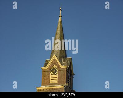 Gros plan de la tour de l'église avec une horloge et un toit pointu devant un ciel bleu vif, egmond aan Zee, pays-bas Banque D'Images