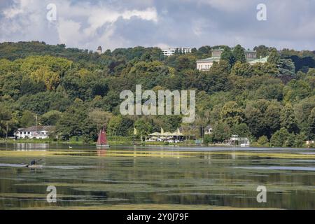 Un lac paisible avec une rive boisée et des maisons en arrière-plan sous un ciel nuageux, Essen, Lac Baldeney, Rhénanie du Nord-Westphalie, Allemagne, Europe Banque D'Images