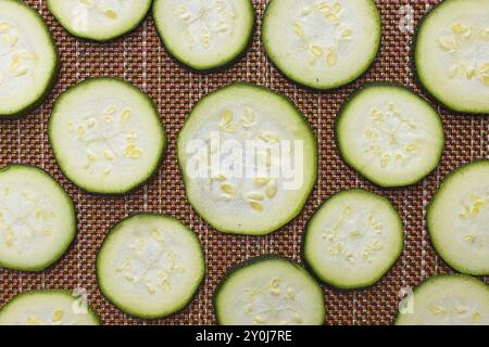 Une photo plate de petites tranches de courgettes disposées sur un tapis séchant au soleil Banque D'Images