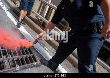 New York, États-Unis. 02 septembre 2024. NEW YORK, NEW YORK - 02 SEPTEMBRE : un policier du NYPD dispose d'une fusée de fumée lors d'une marche pro-palestinienne en soutien à Gaza, le 2 septembre 2024 à New York, le jour de la fête du travail. La manifestation a eu lieu un jour après un rassemblement à Central Park pour pleurer le meurtre par le Hamas de six otages israéliens à Gaza. Les manifestants ont appelé à anéantir l'État d'Israël. Crédit : Ron Adar/Alamy Live News Banque D'Images