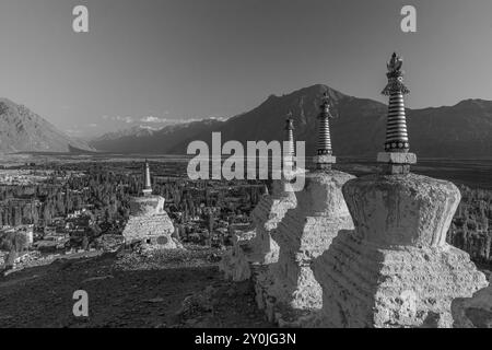 Beaucoup de stupas blancs dans une rangée avec des chaînes de montagnes en arrière-plan. Banque D'Images