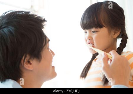 Père aidant la fille à se brosser les dents Banque D'Images