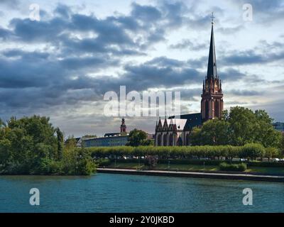 L'église évangélique des trois Rois à Francfort-sur-le-main avec un ciel nuageux et la rivière au premier plan Banque D'Images