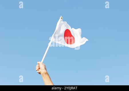 La main d'un homme acclamant en agitant le drapeau japonais Banque D'Images