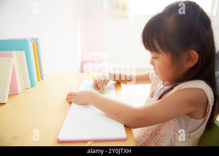 Profil d'une fille dessinant une image sur le bureau dans une chambre d'enfants Banque D'Images