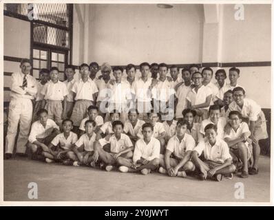 Professeur d'histoire Mr. R.G. Barker avec des élèves de classe posent pour un portrait de groupe à Victoria School à Singapour, au milieu des années 1950 Banque D'Images