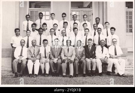 Les enseignants de l'école Victoria à Singapour posent pour un portrait de groupe au milieu des années 1950, y compris Mr. R.G. Barker portant un blazer foncé au premier rang Banque D'Images