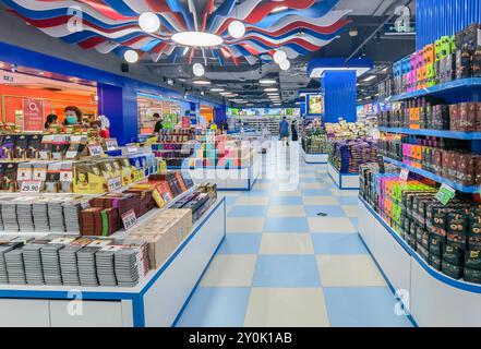 Shenzhen, Chine - 02 septembre 2024 : Une allée de supermarché bien éclairée à Shenzhen, Chine, remplie d'étagères de chocolats en boîte. Le plafond est orné Banque D'Images